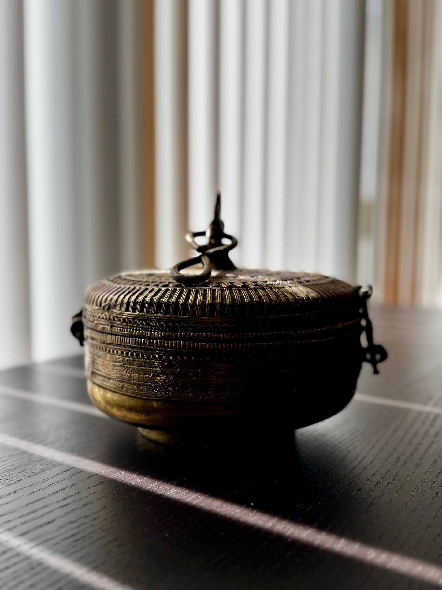 Decorative brass box with intricate designs on a dark surface with light background