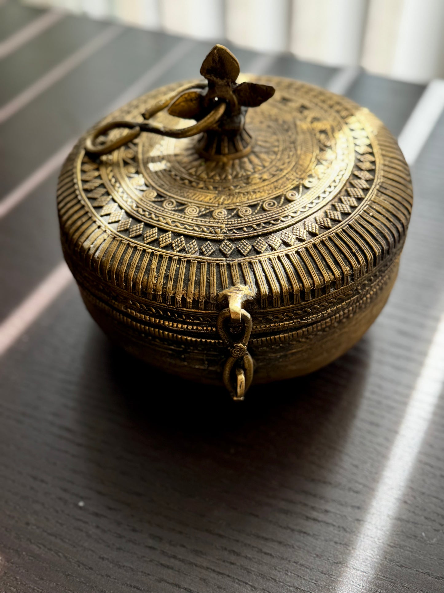 Decorative brass box with intricate patterns on a dark surface