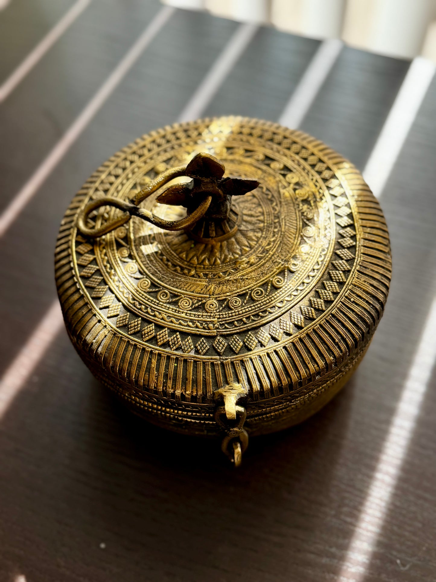 Decorative brass box with intricate patterns on a reflective surface