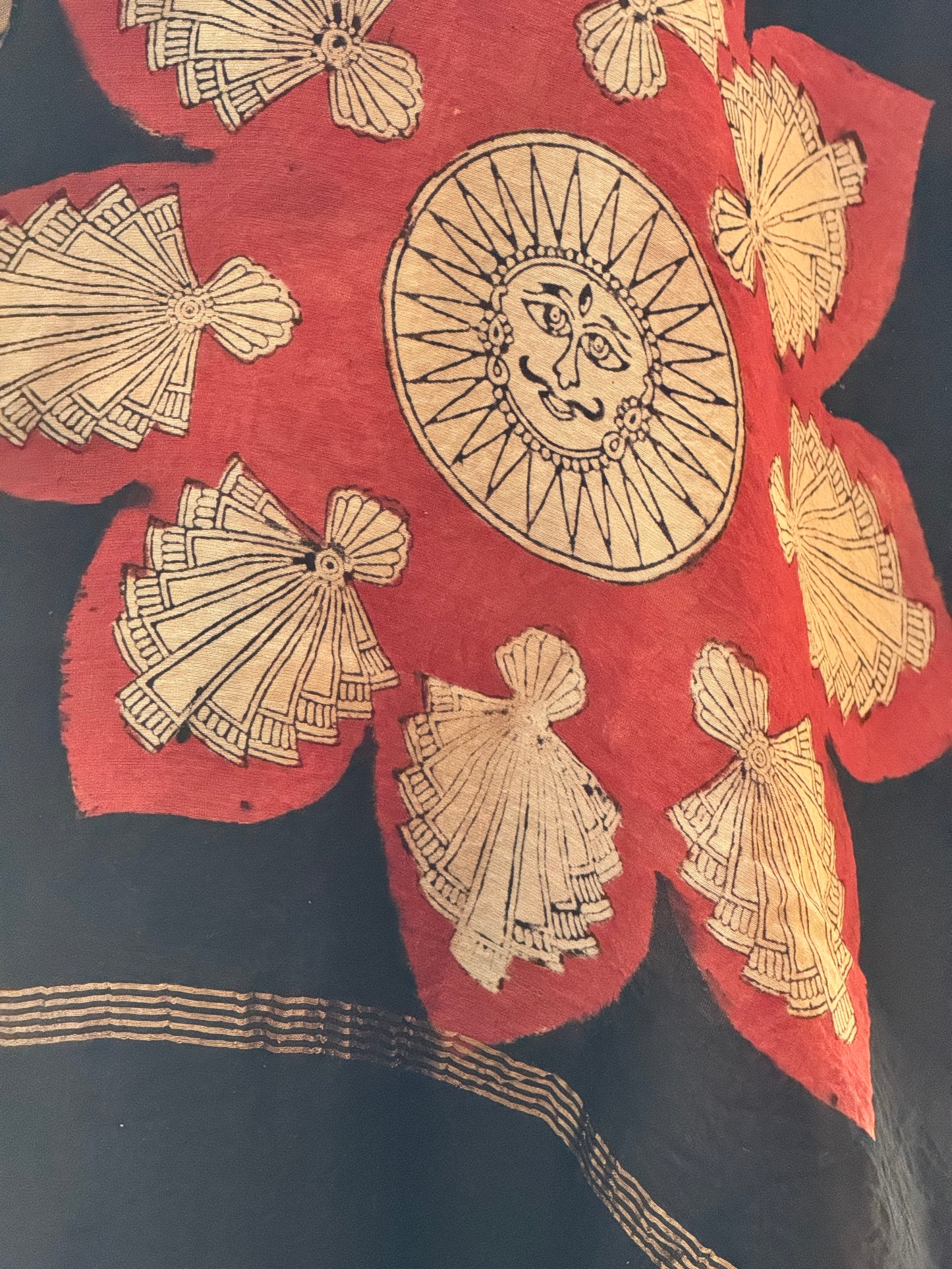 Close up of Decorative stole with gold sun and fan patterns in Mata ni Pachhedi str style hand painted on a red and black background
