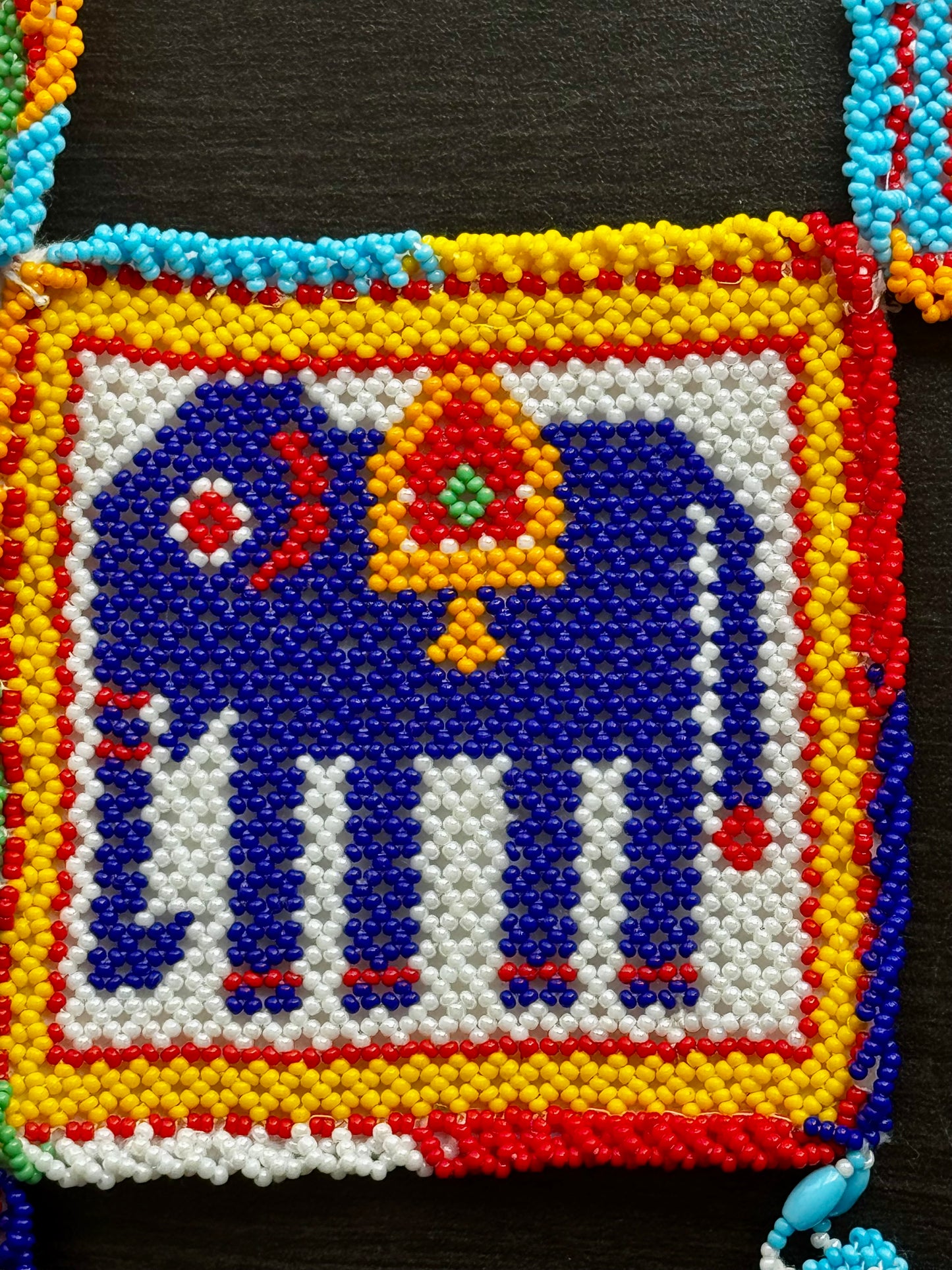 Colorful close up of Motikaam. Strung pearls art design of an elephant with a decorative umbrella on a black background