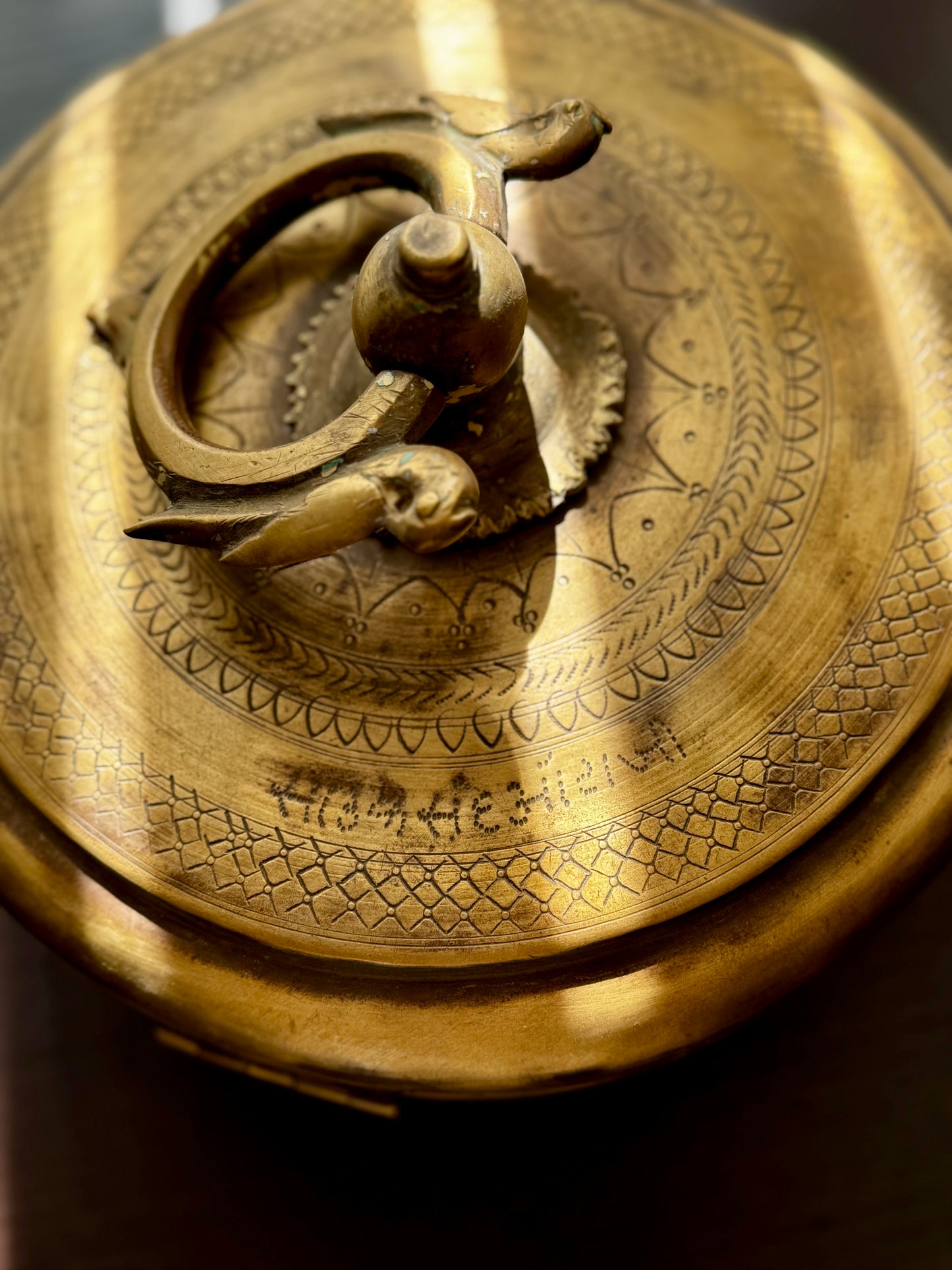 Close-up of a detailed brass box/container with engraved patterns and figures.