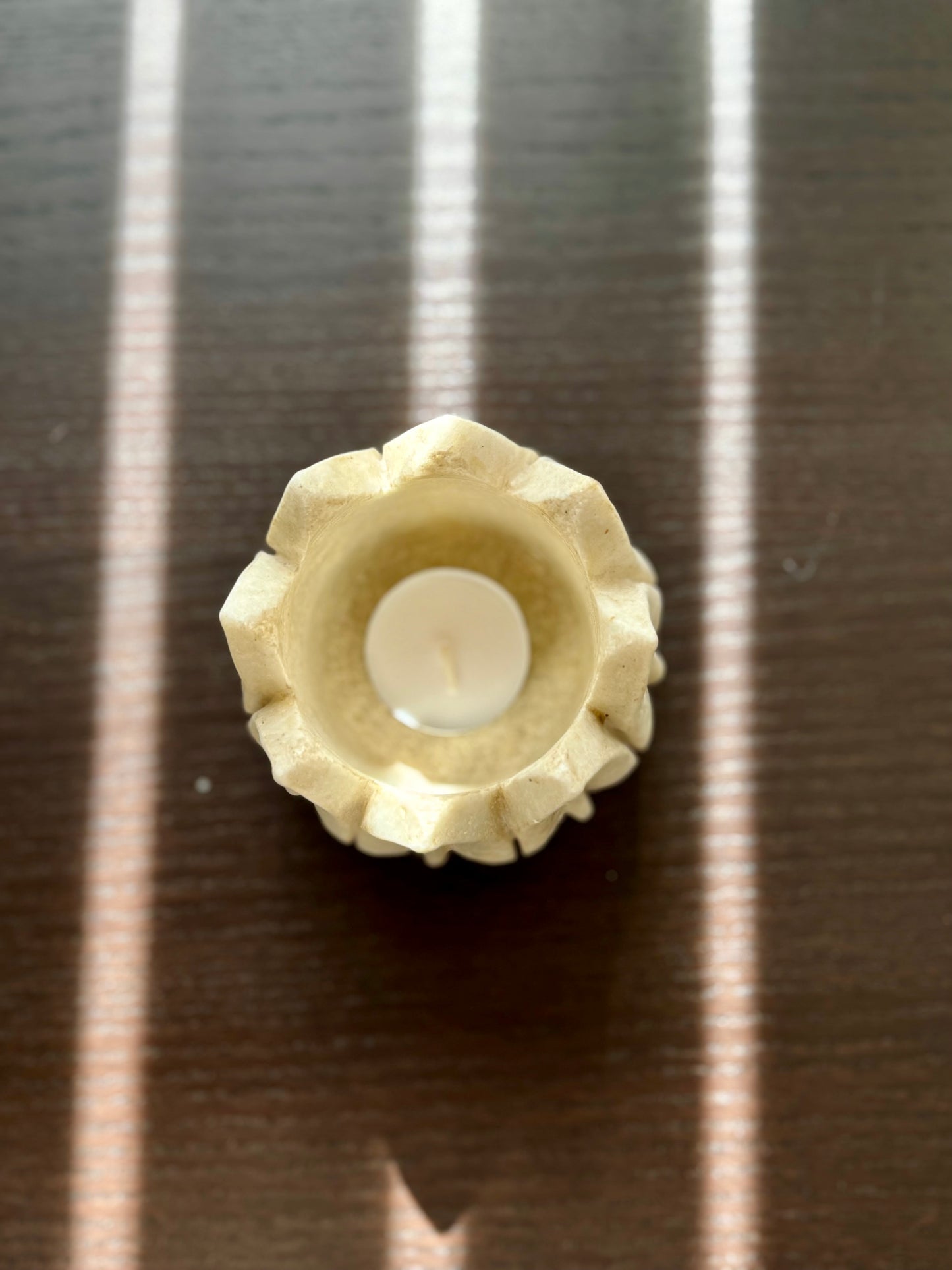 Decorative marble candle holder with a white candle on a striped surface