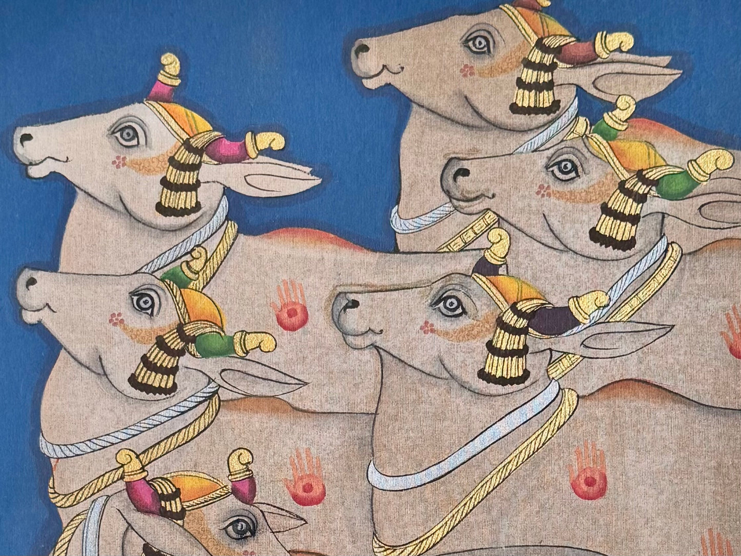Decorative Pichwai painting of four cows with colorful ornaments on a blue background