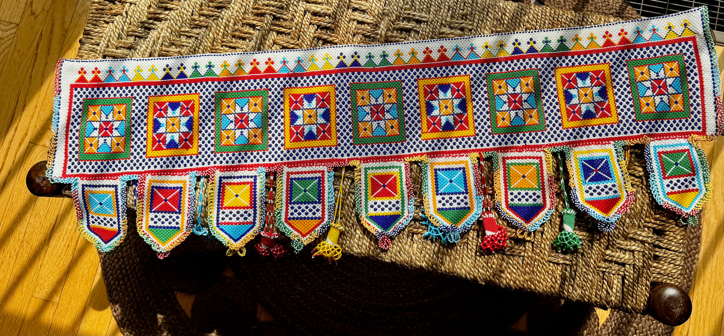 Decorative Motikaam - strung Pearl work wall or door hanging with colorful patterns on a wooden surface