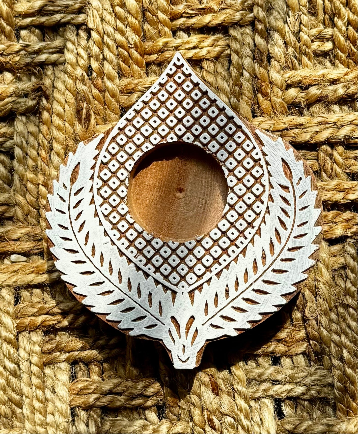 Decorative hand engraved wooden block tea light holder on a textured woven surface