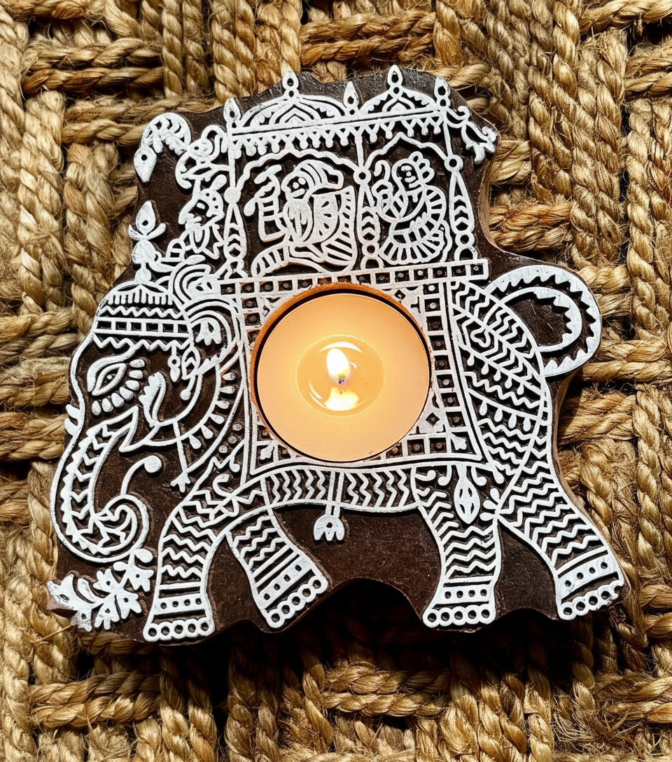 Decorative hand engraved wooden block tea light holder in elephant shape with intricate white patterns on a textured brown background