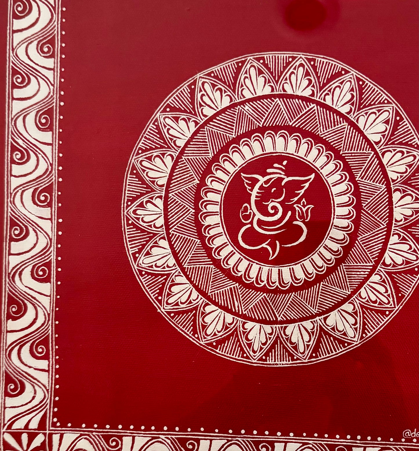 Decorative red Aipan art close up cover with white mandala design and Ganesha