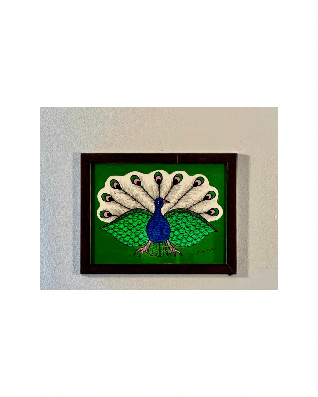 Framed Gond artwork of a peacock on a green background