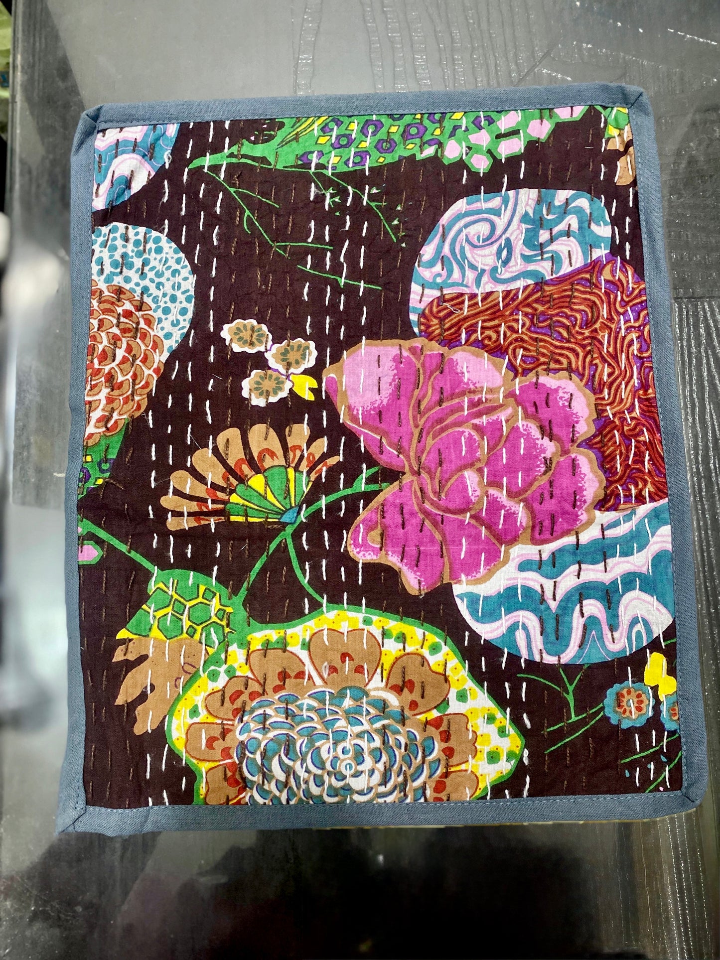 Colorful floral patterned Kantha work placemat on a dark background