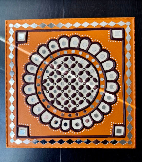 Decorative Lippankaam art with a central circular design on an orange background