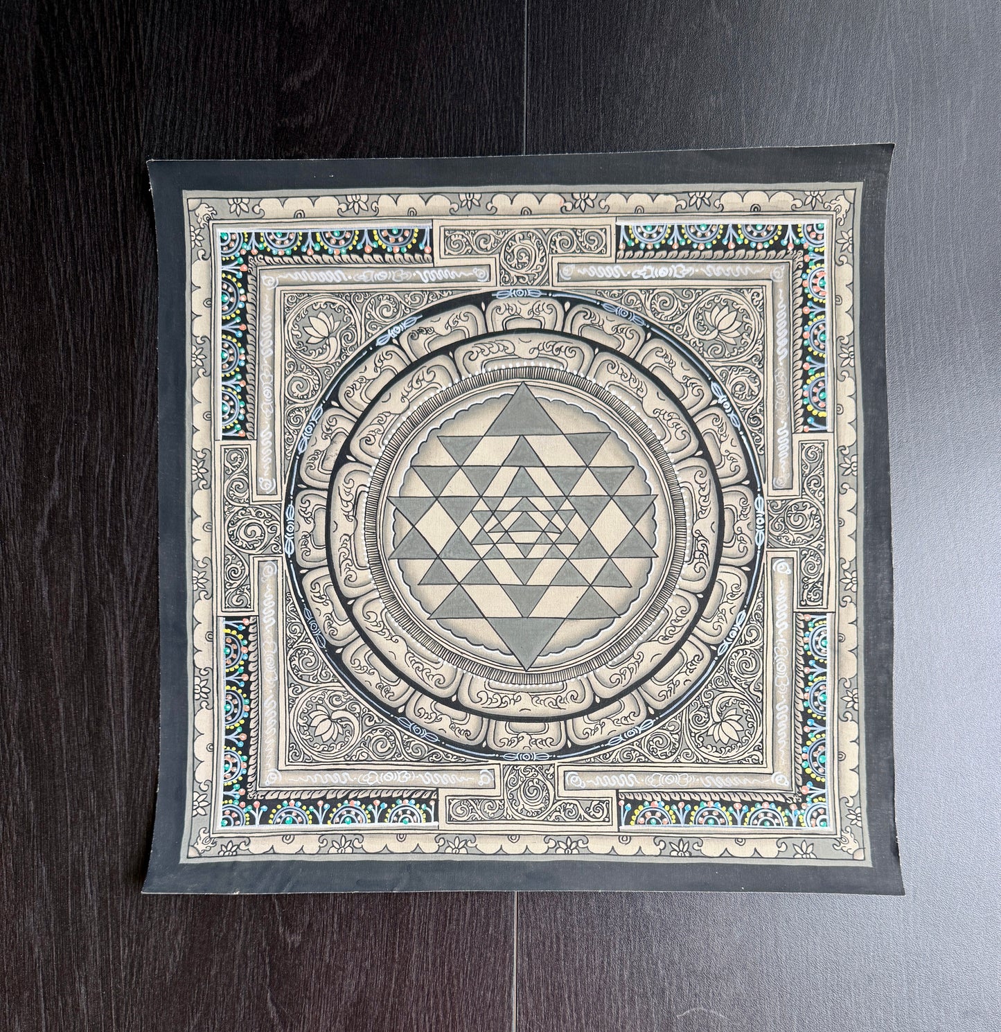 Shree yantra painting in Thangka art style with a geometric design on a wooden surface