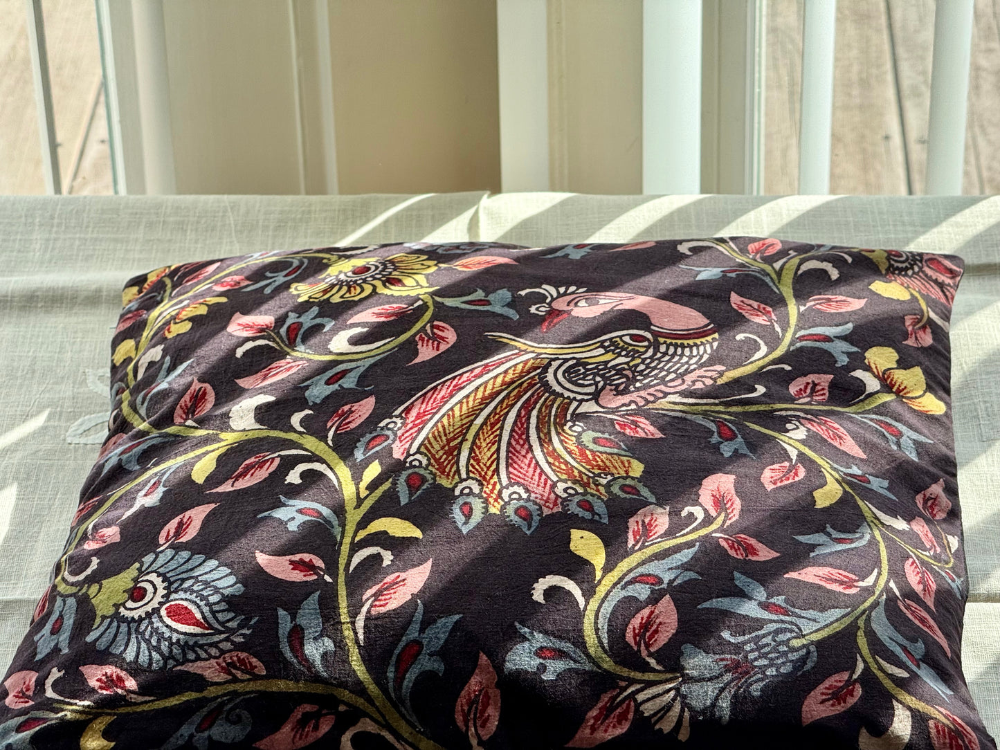 A set of artisanal Kalamkari hand-painted cushion covers with vibrant and intricate patterns laid out on a surface.