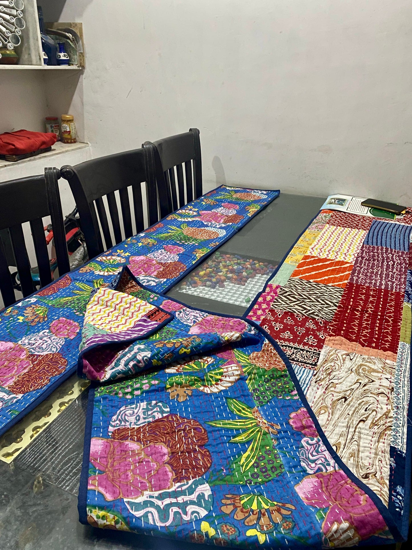 Colorful Kantha work reversible table runners with floral patterns on a table with chairs in a room.