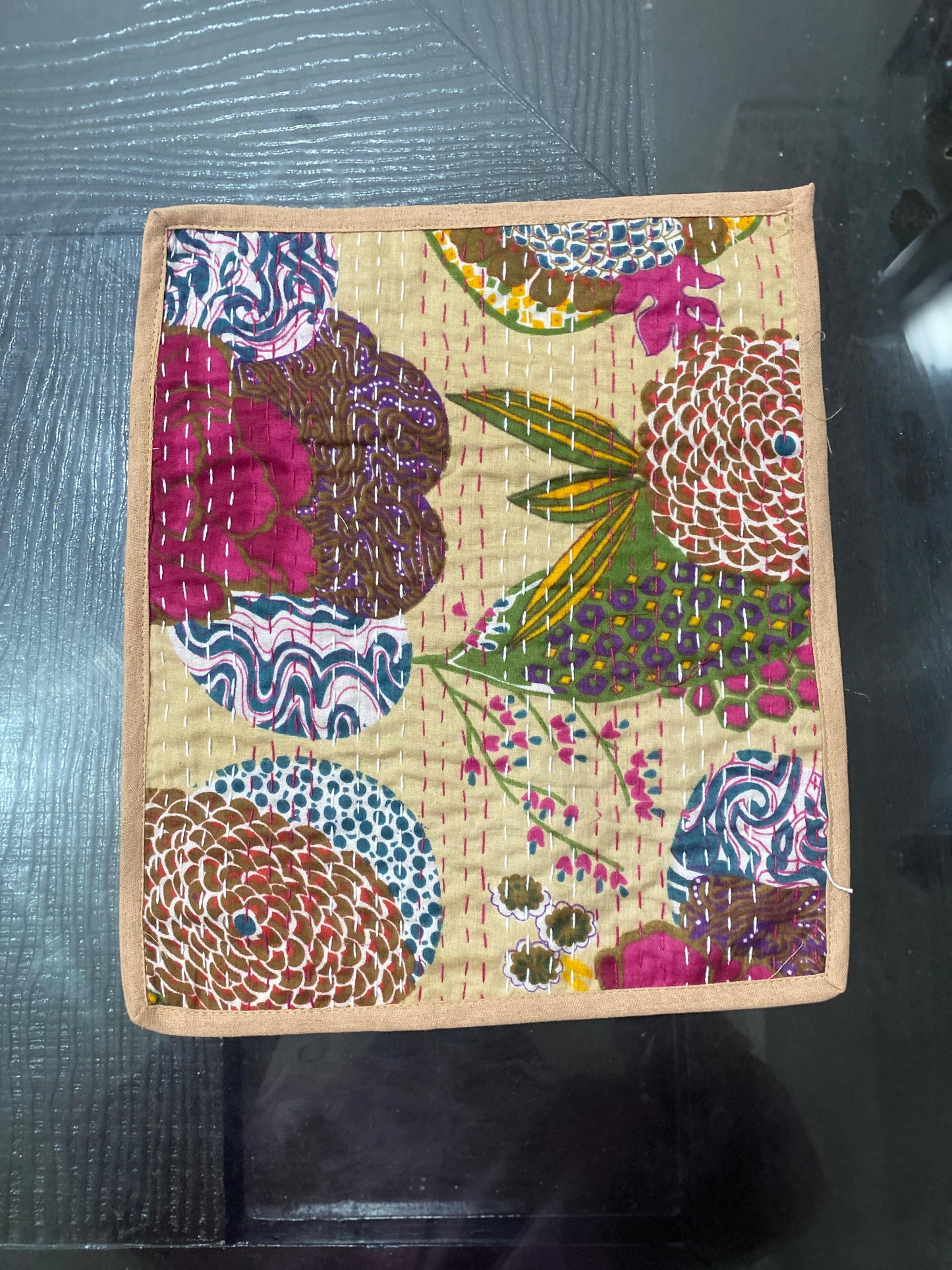 Colorful floral fabric Kantha work placemat on a textured surface
