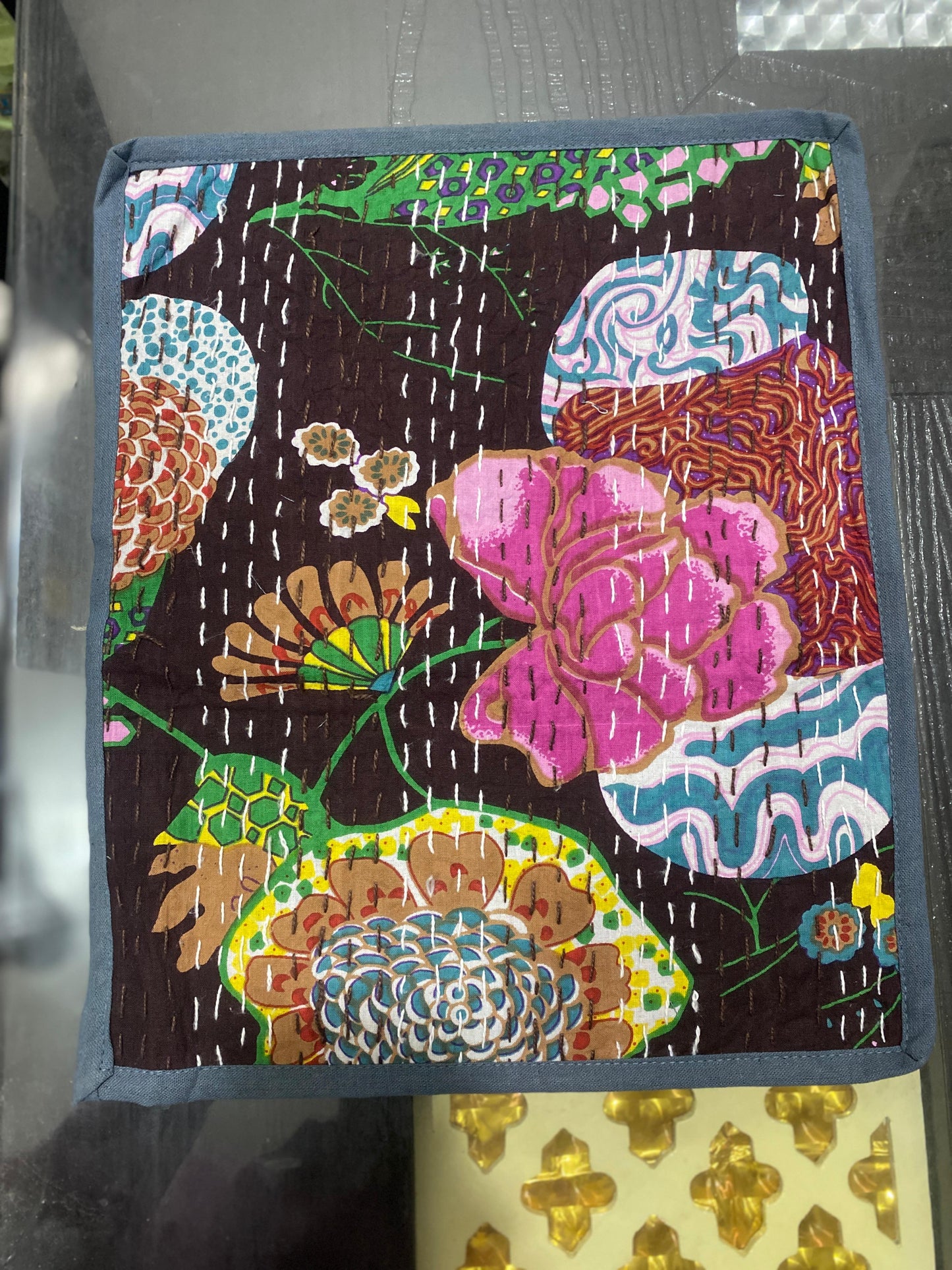 Colorful floral Kantha work patterned placemat on a dark background