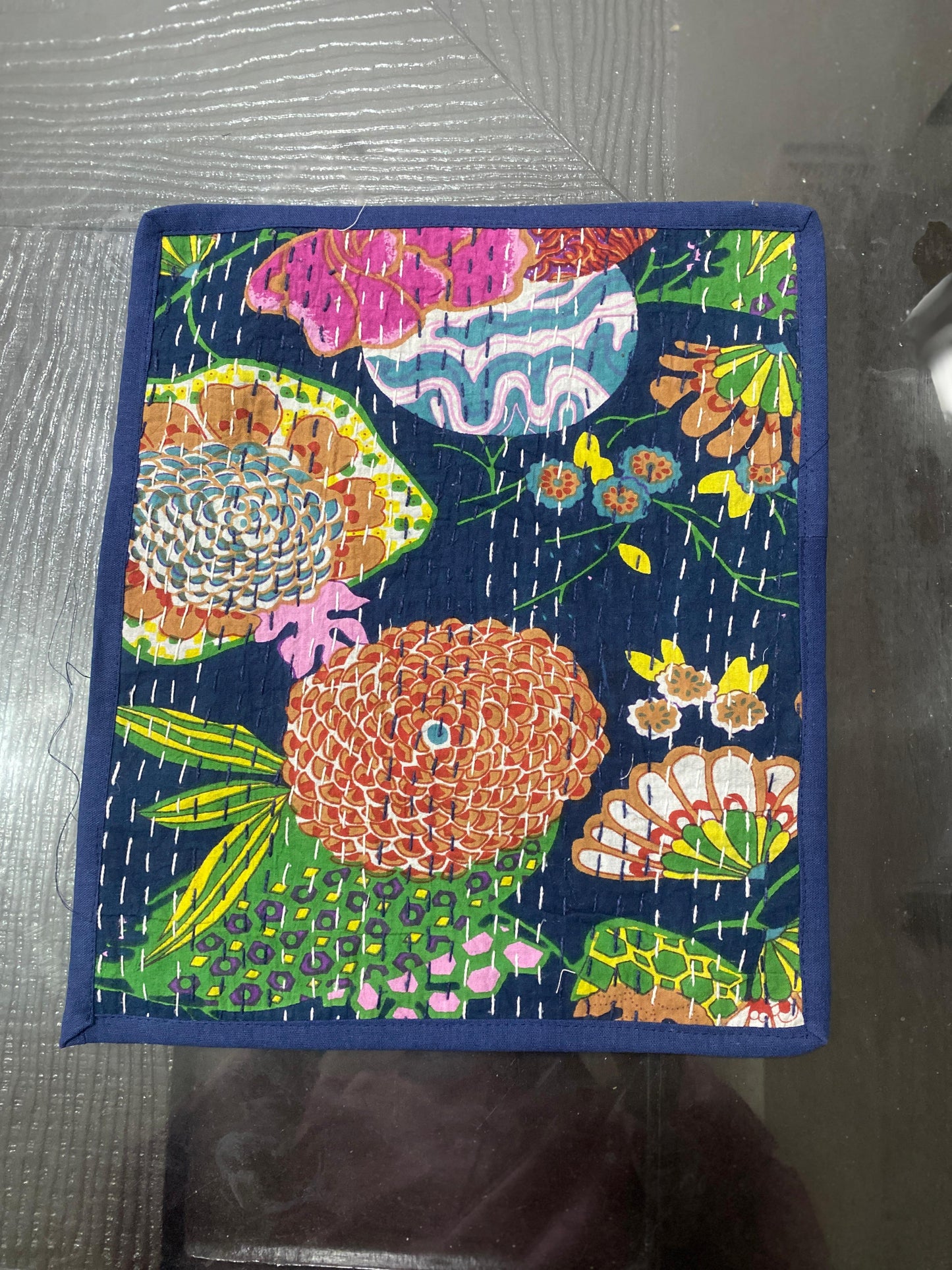 Colorful floral patterned fabric Kantha work placemat on a dark background