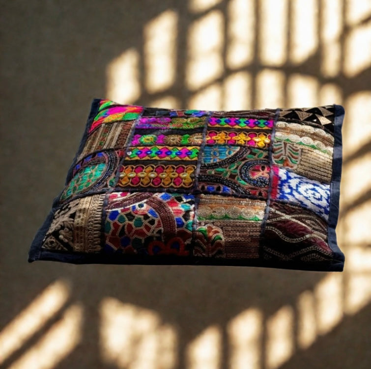 Cushion cover crafted from Khambhadia patchwork, showcasing a collage of vintage fabrics, intricate embroidery, and mirror accents in bold, vibrant colors.