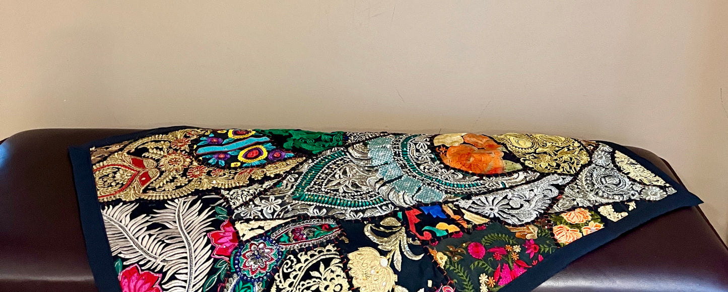 Decorative table runner with intricate Khambhadia patchwork patterns on a wooden surface.
