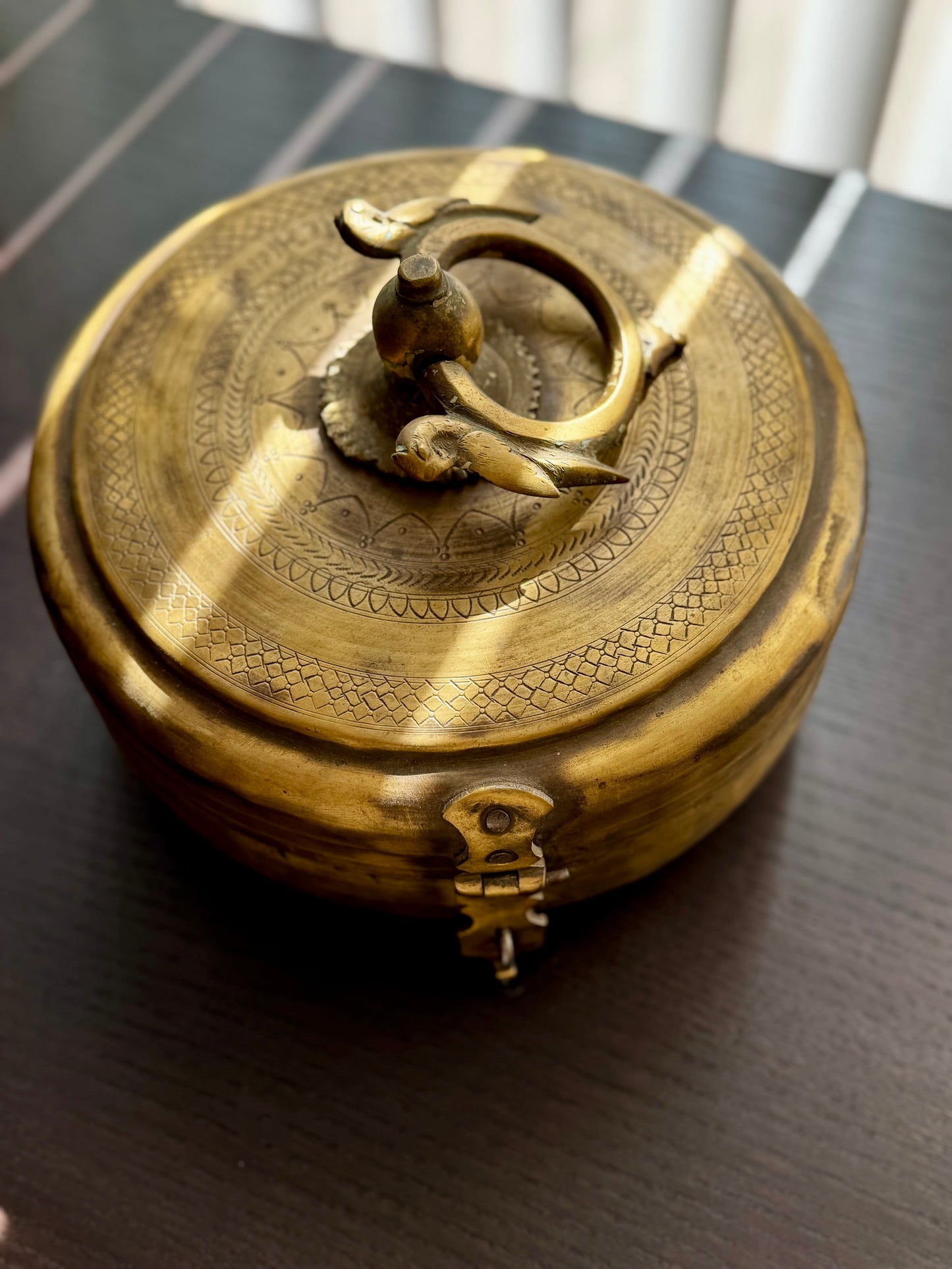 Brass decorative box with intricate designs on a dark surface