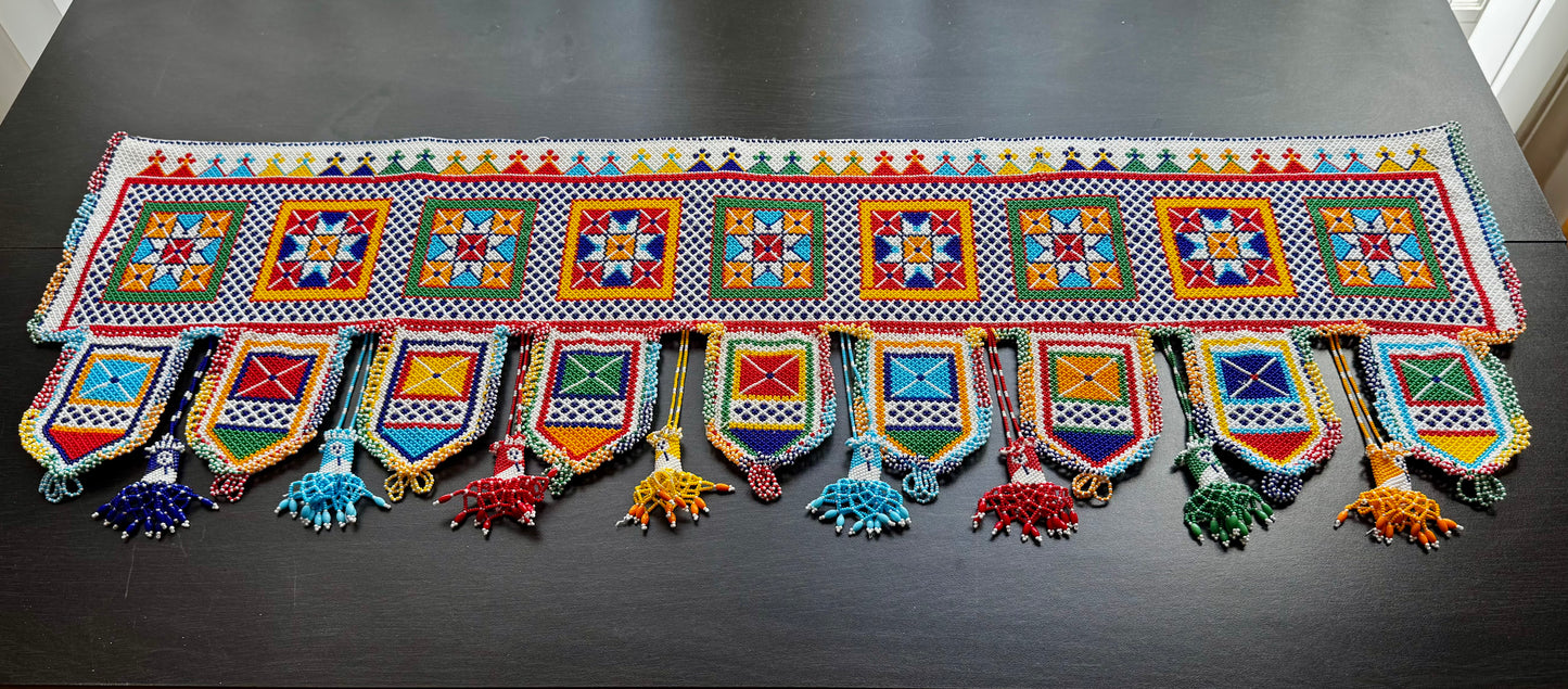 Colorful decorative Motikaam valance with patterns and tassels on a dark surface