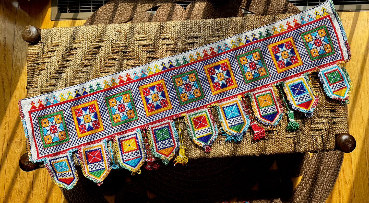 Decorative Motikaam - strung Pearl work wall hanging with colorful design on a textured fabric background
