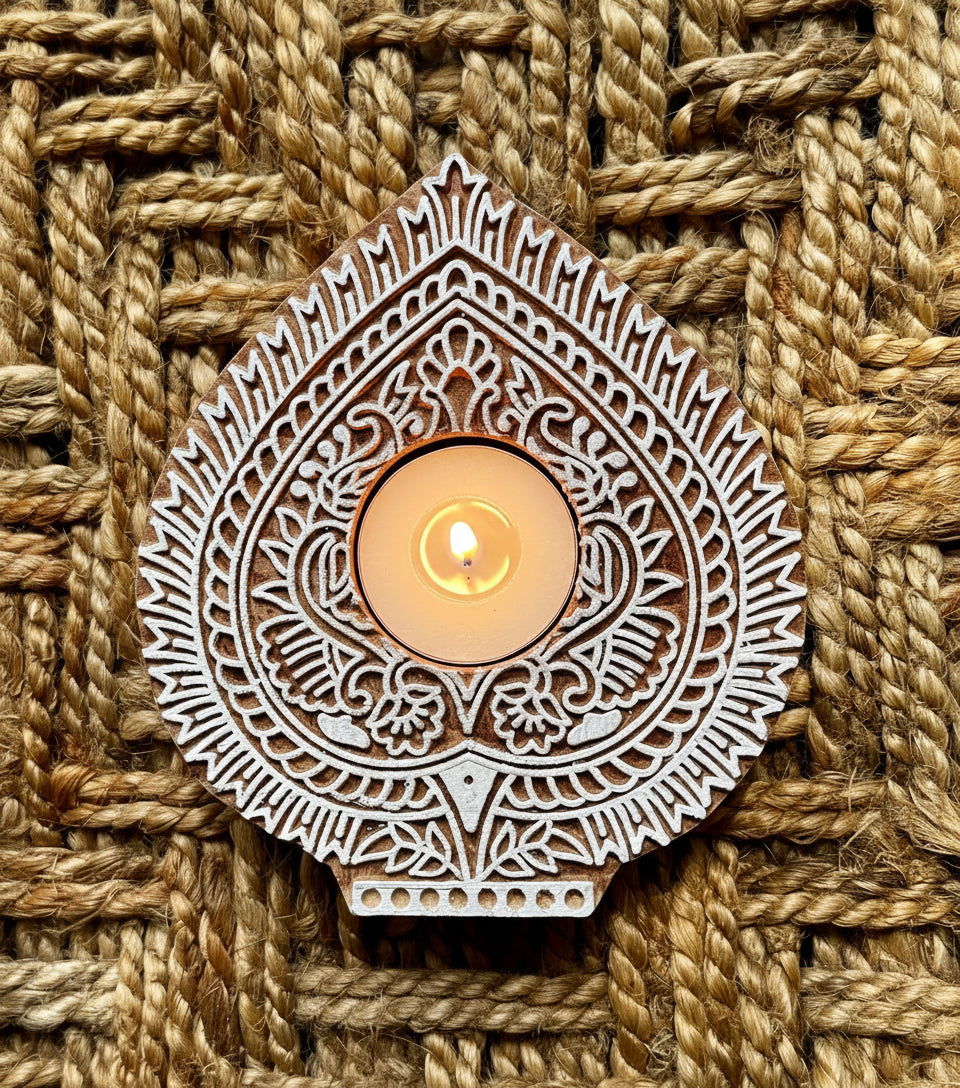 Decorative hand engraved wooden block tea light holder in leaf shape with intricate patterns on a textured woven background