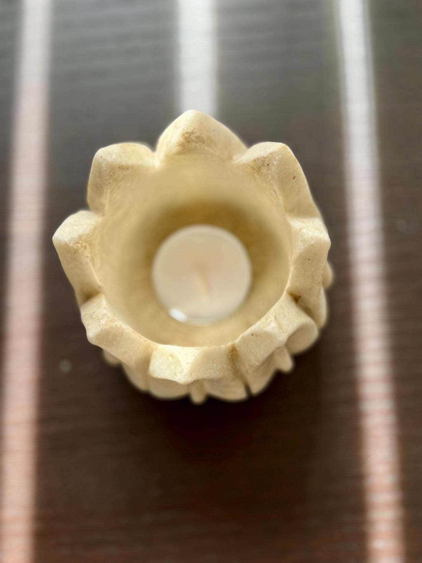 Decorative marble candle holder with a white candle on a metallic surface