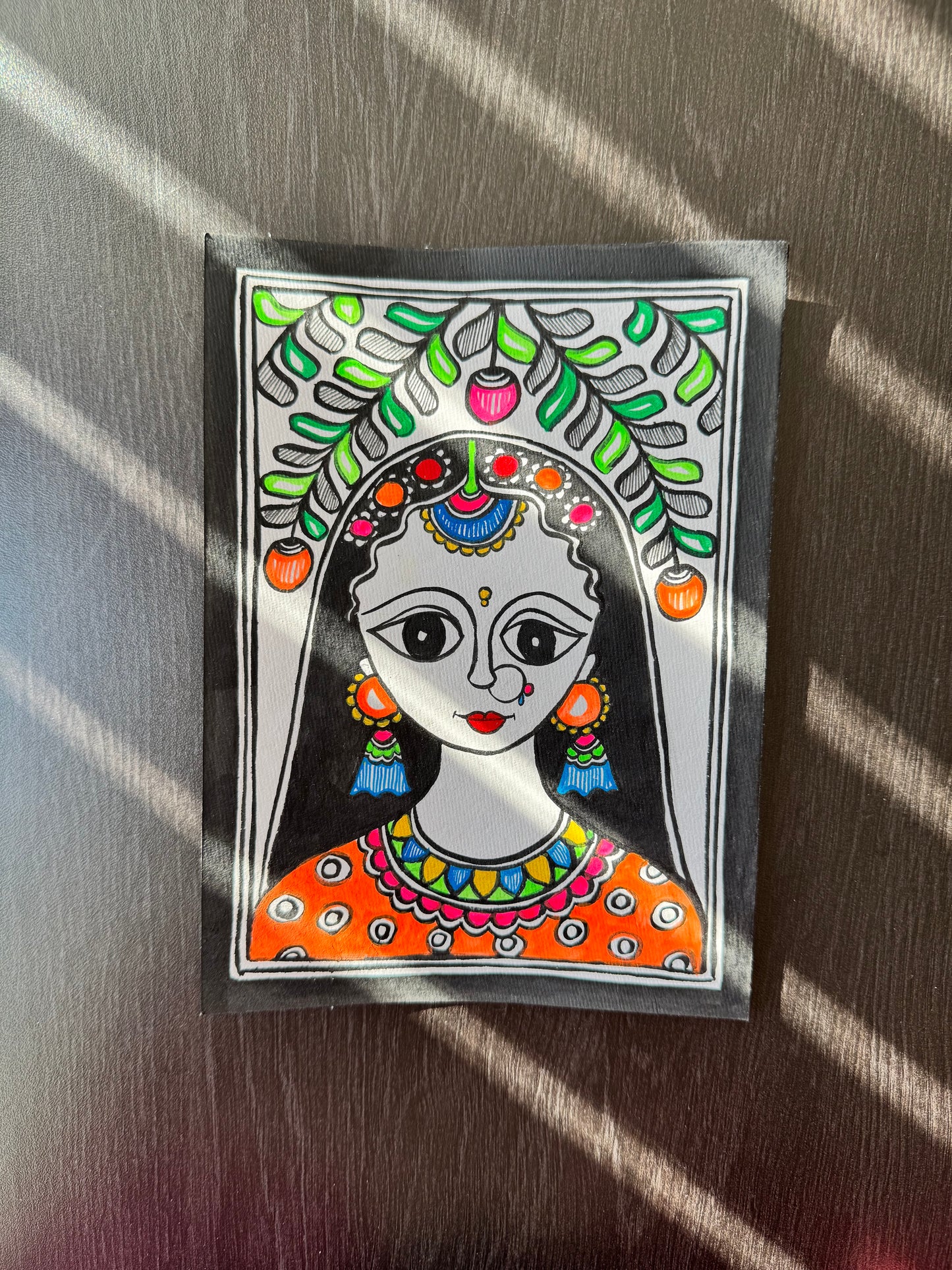Colorful and decorative Madhubani art painting with a young girl’s face on paper