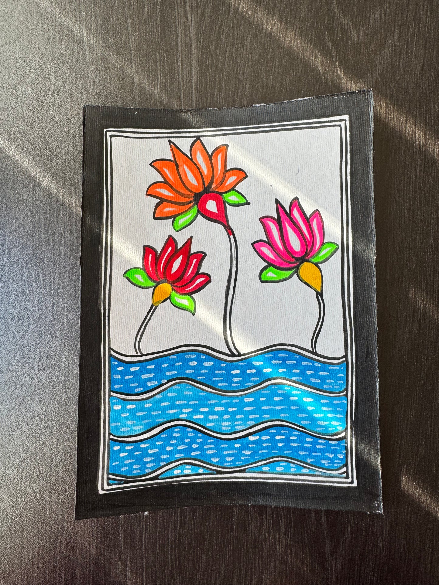 Colorful Madhubani art drawing of lotus flowers and water