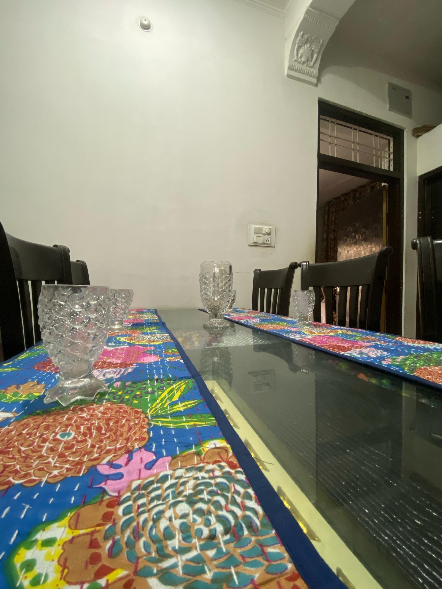 Dining table with colorful table runners and chairs in a room.