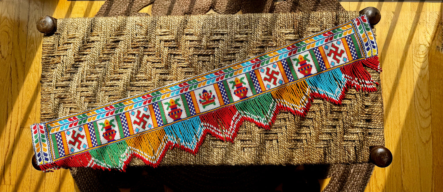 Decorative Motikaam - strung Pearl work wall hanging with colorful design on a textured fabric background Colorful decorative border with patterns on a woven surface