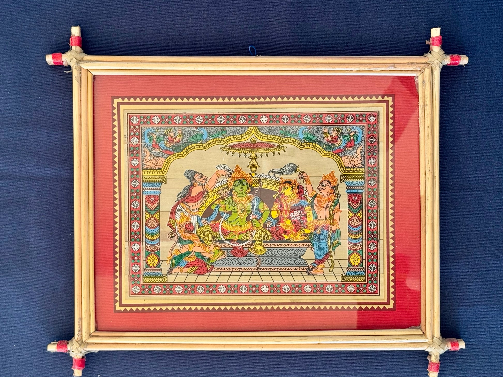 Hand-painted Pattachitra art featuring traditional motifs and mythological stories, elegantly framed with unique bamboo detailing.