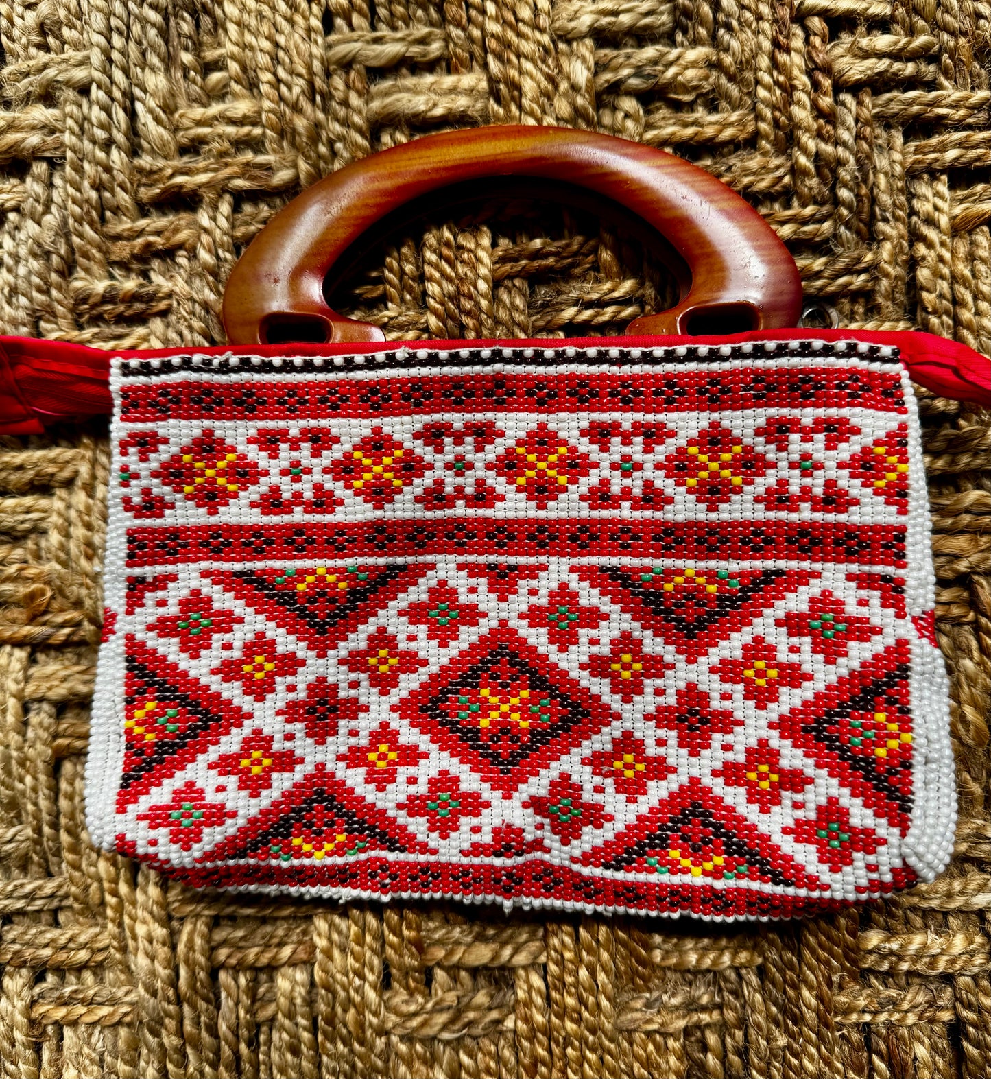Decorative Motikaam - strung Pearl work Handbag with geometric pattern and wooden handle on a woven background