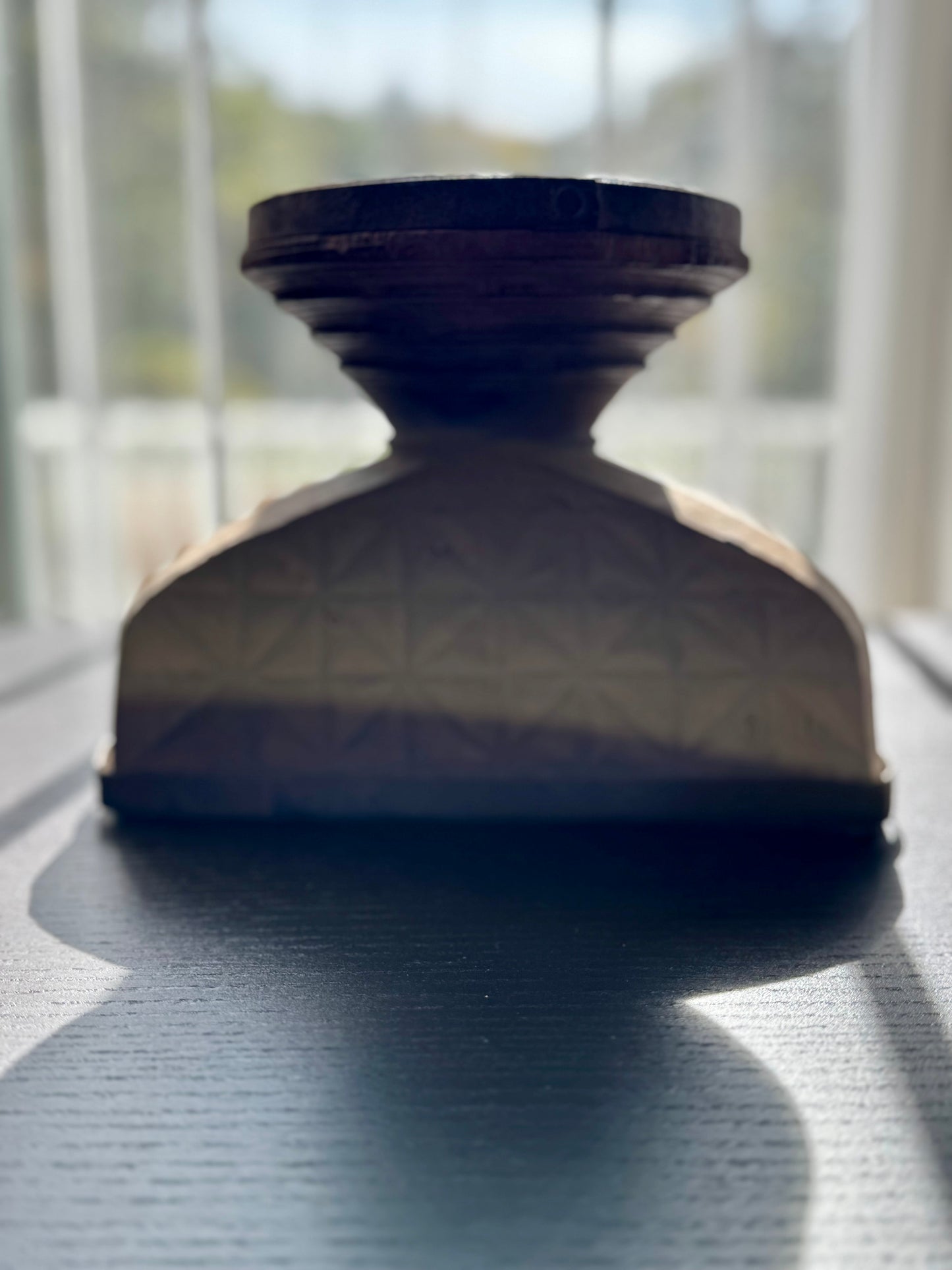 Decorative candle holder with textured surface on a reflective surface