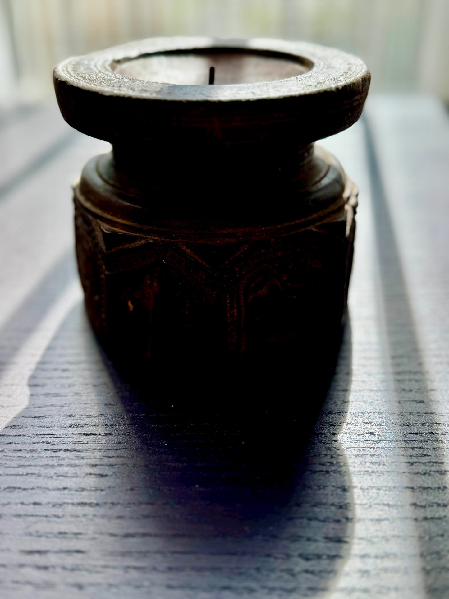 Dark wooden candle holder on a textured surface