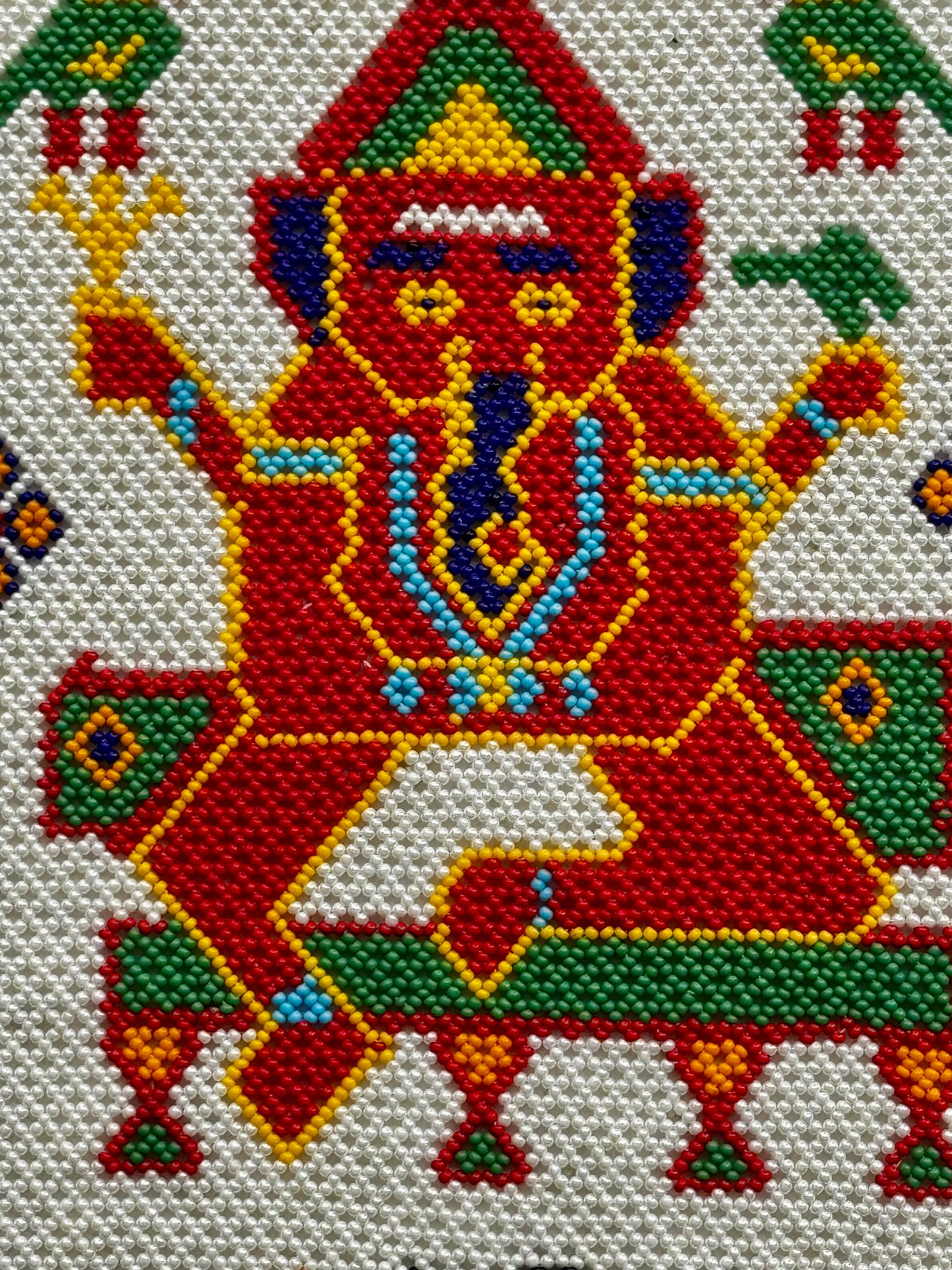 Colorful motikaam artwork of a deity with intricate patterns on a white background