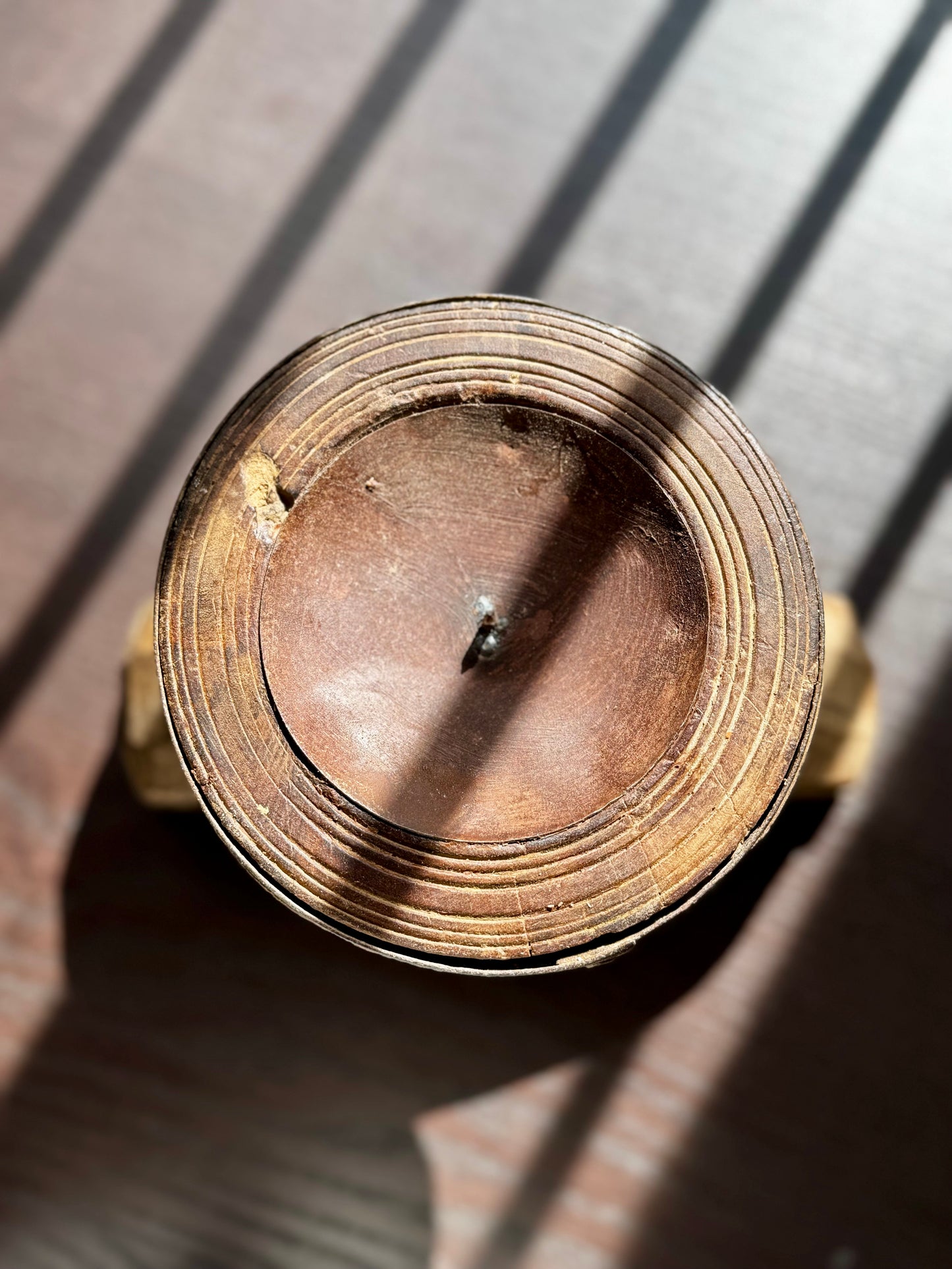 Close-up of a brass-colored metal and wood object with a central shaft on a dark background