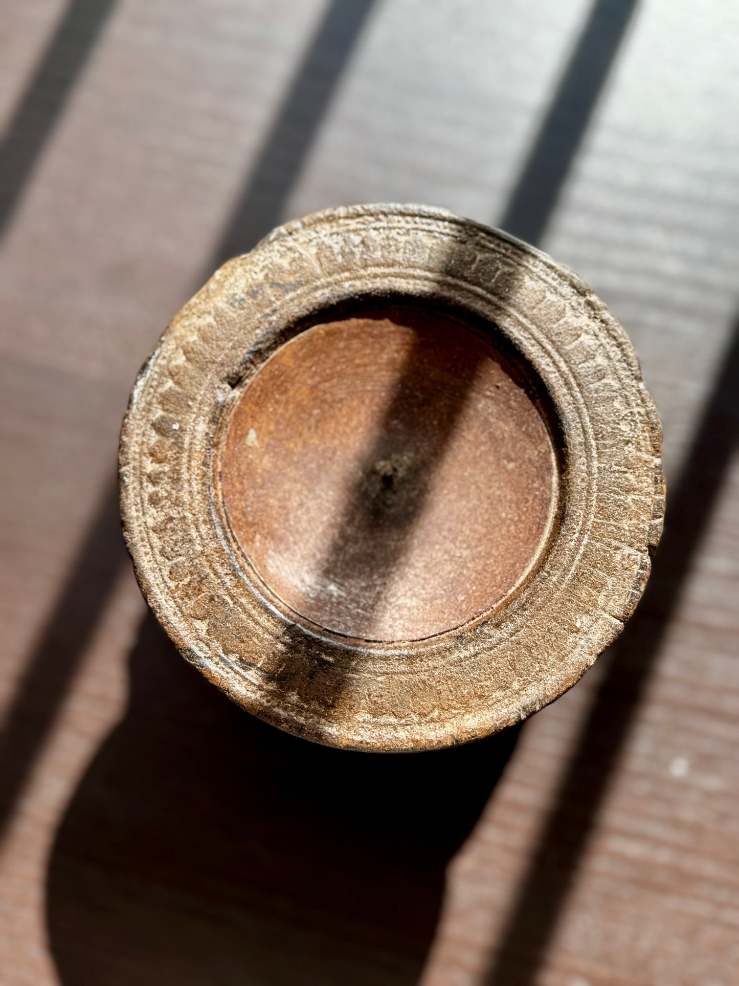 Close-up of a textured, round metal and wood object on a dark surface