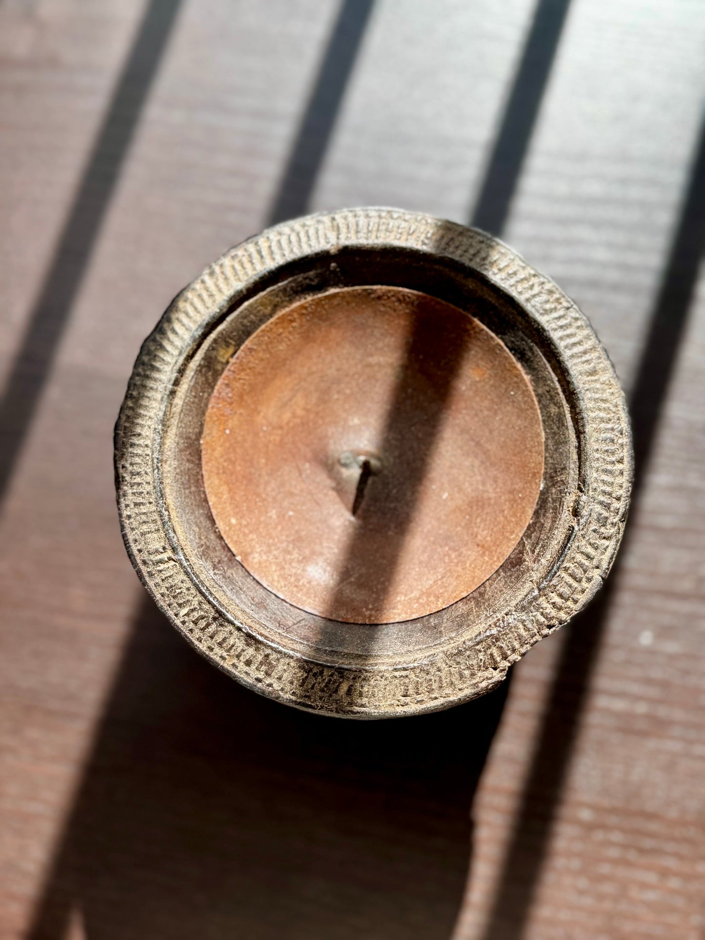 Close-up of a metallic object with intricate design on a wooden surface