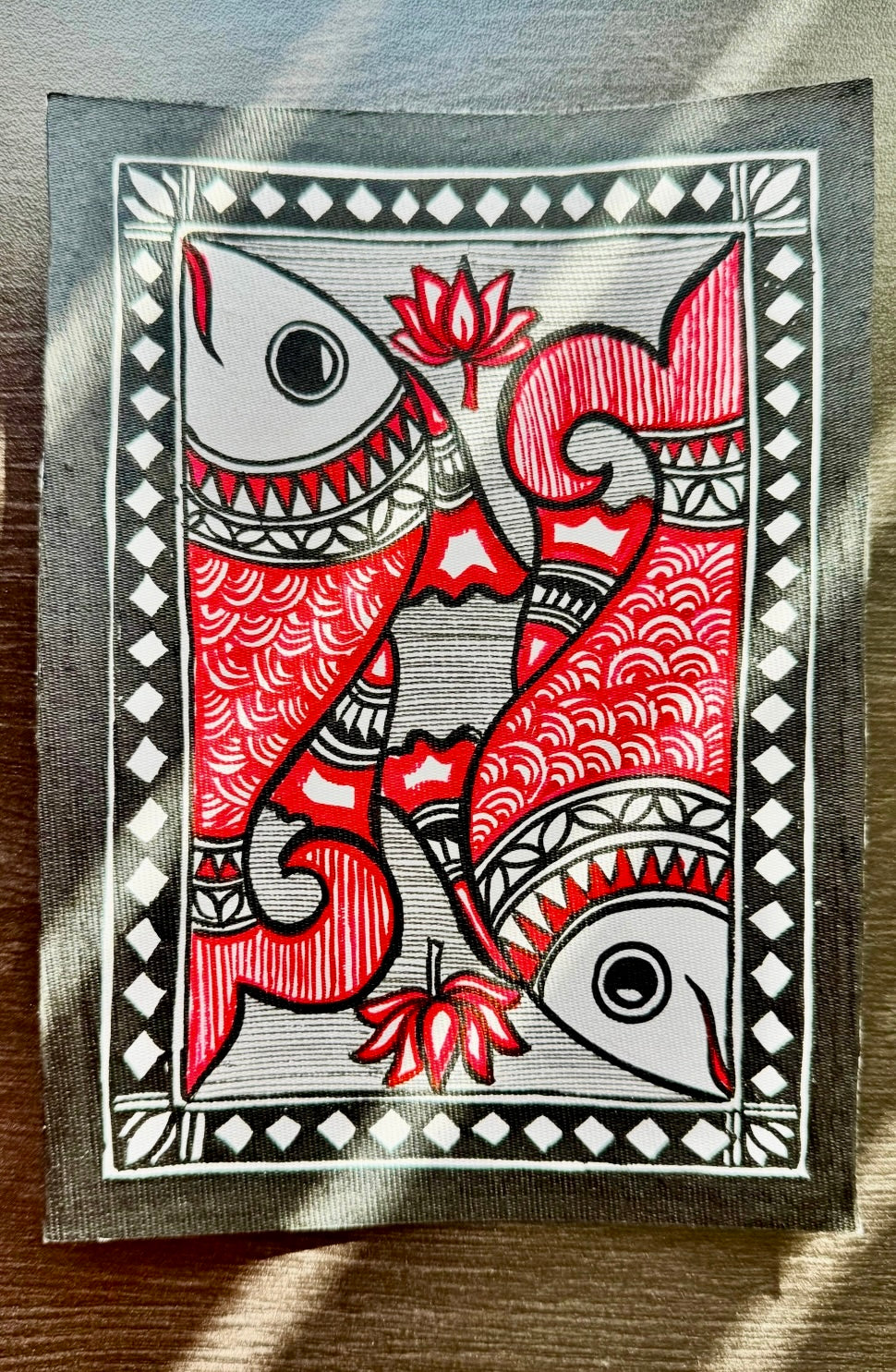 Madhubani art painting with red and black fish design on a white background