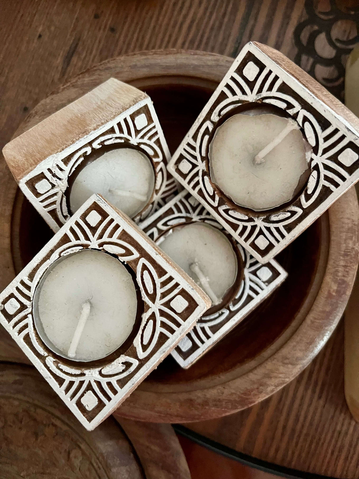 Hand-carved wooden tea light holders in various shapes, featuring intricate designs and natural finishes, adding a rustic, artisanal touch to your home decor.