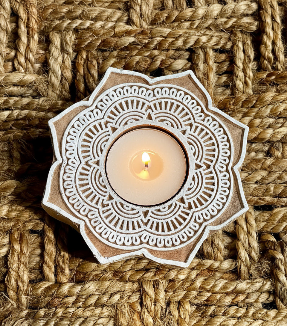 Decorative hand engraved wood tea light holder with intricate white patterns on a woven brown background