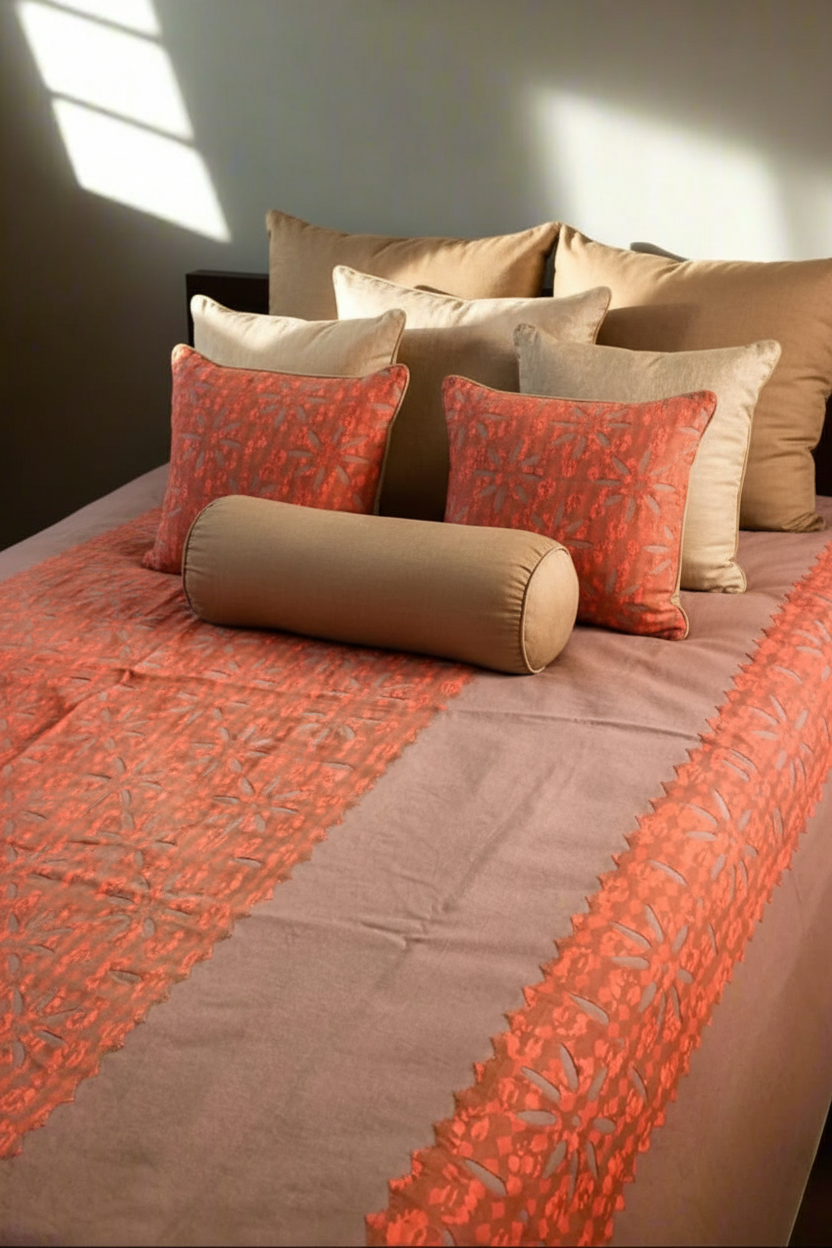 Bed with decorative pillows and a patterned blanket in warm tones.