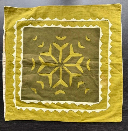 Decorative green fabric with yellow patterns on a dark surface