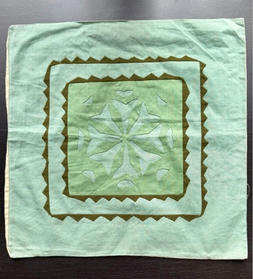 Green quilted square with a star pattern on a dark surface