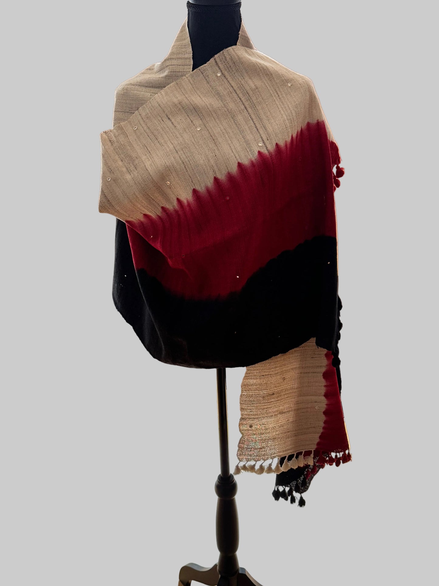 Mannequin wearing a red and beige striped stole in front of a mirror.