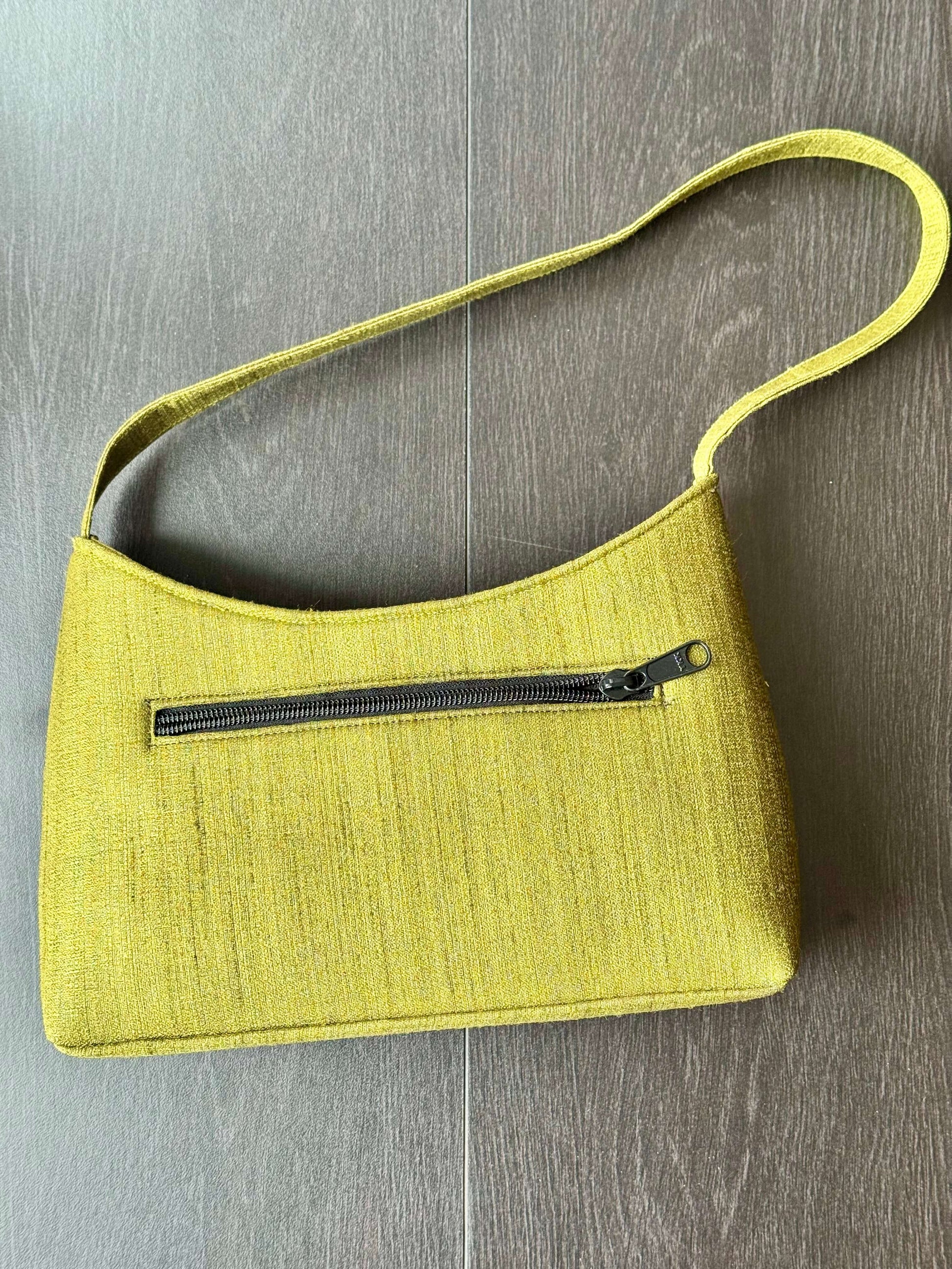 Green handbag with a zipper on a wooden surface