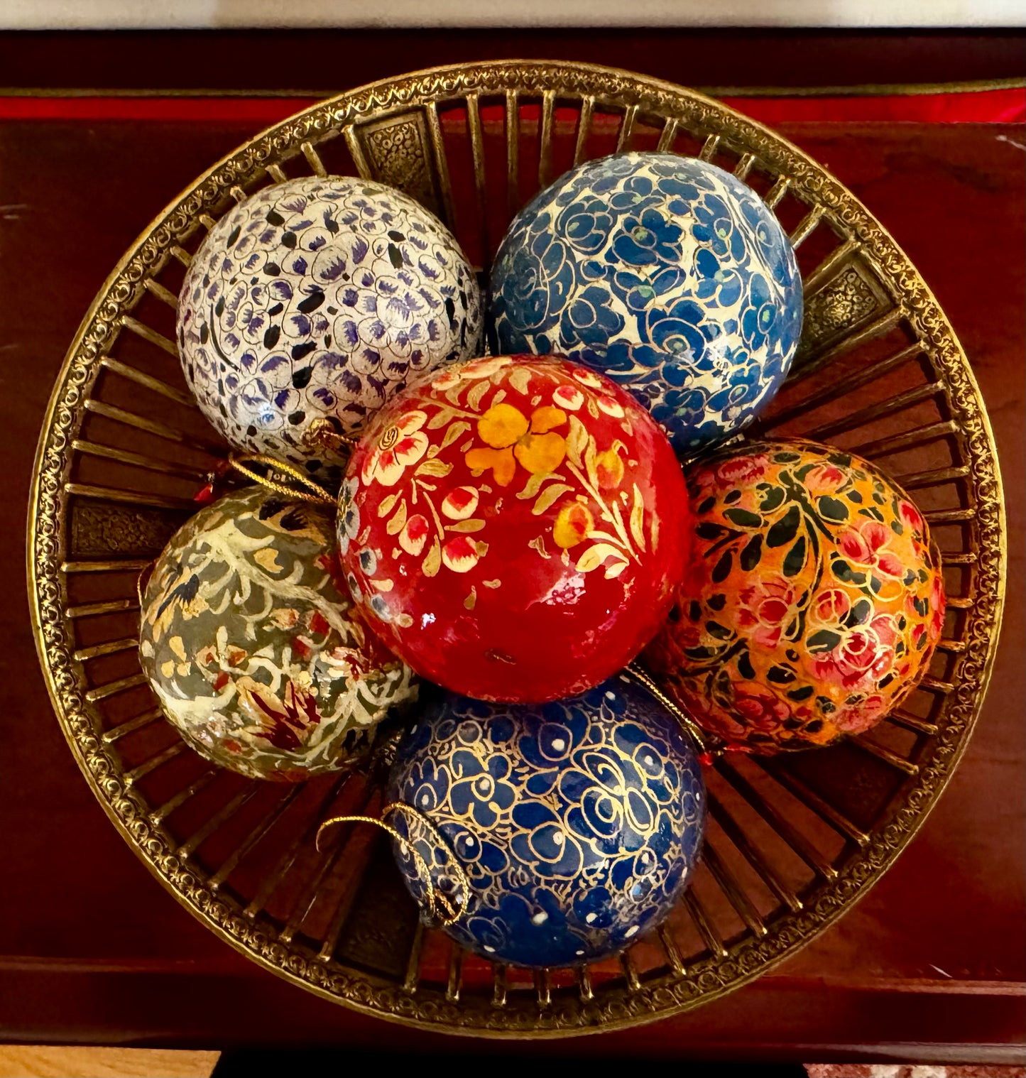 Decorative Christmas balls with floral patterns on a gold tray.
