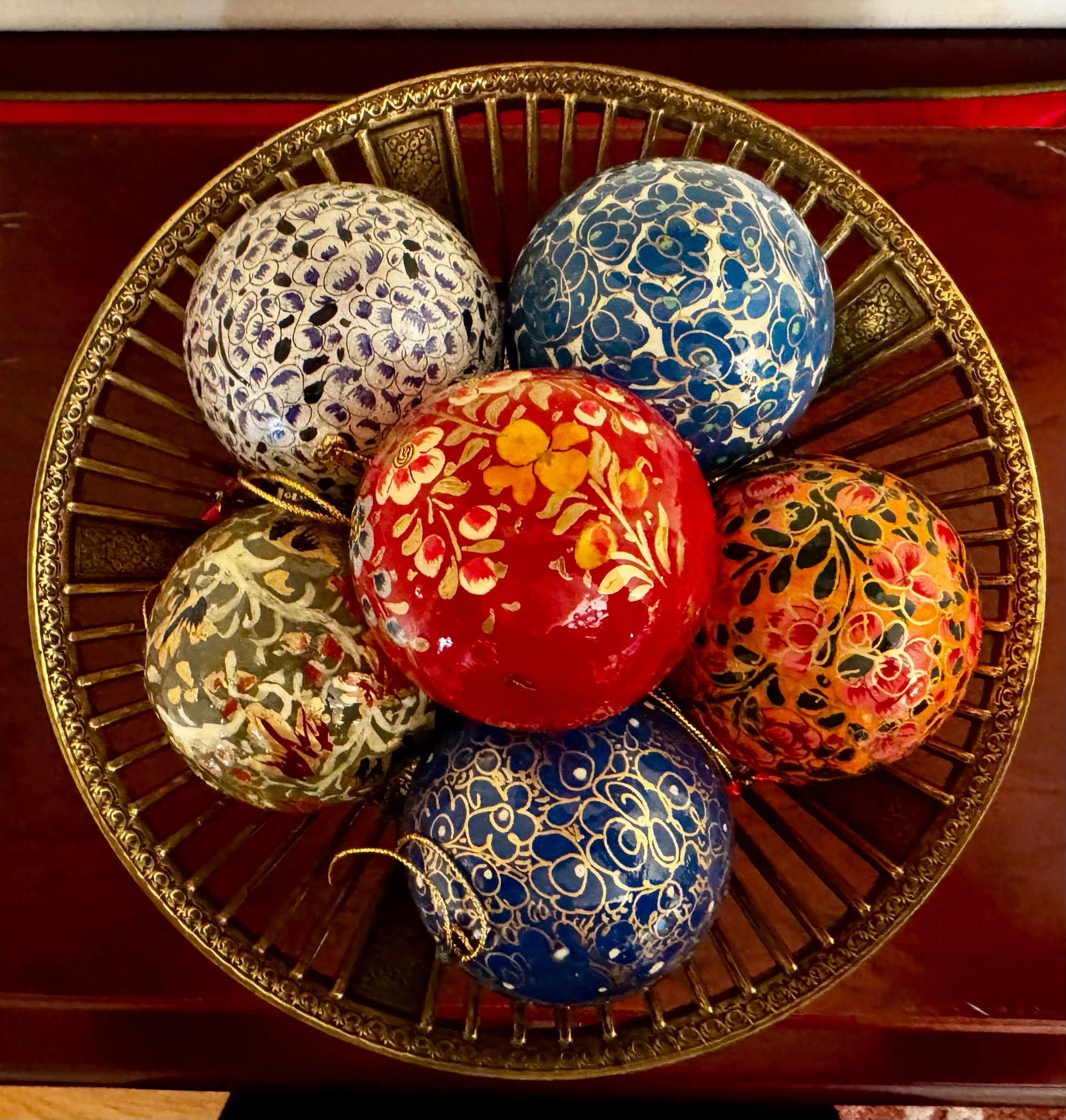 Decorative Christmas balls with floral patterns on a gold tray.